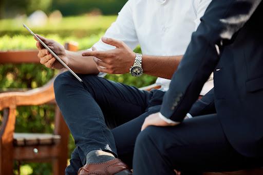 A professional reviews a business proposal made with proposal automation software with a coworker on a tablet.
